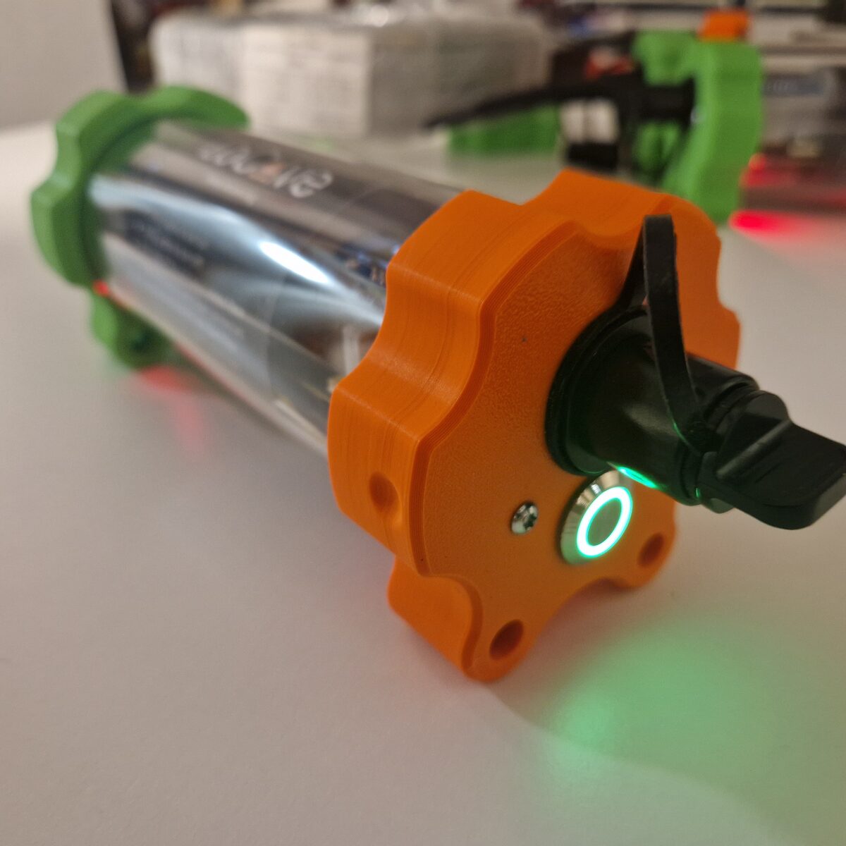 The end cap of a node with its single push button, lit by a green ring, and a capped optical connector.