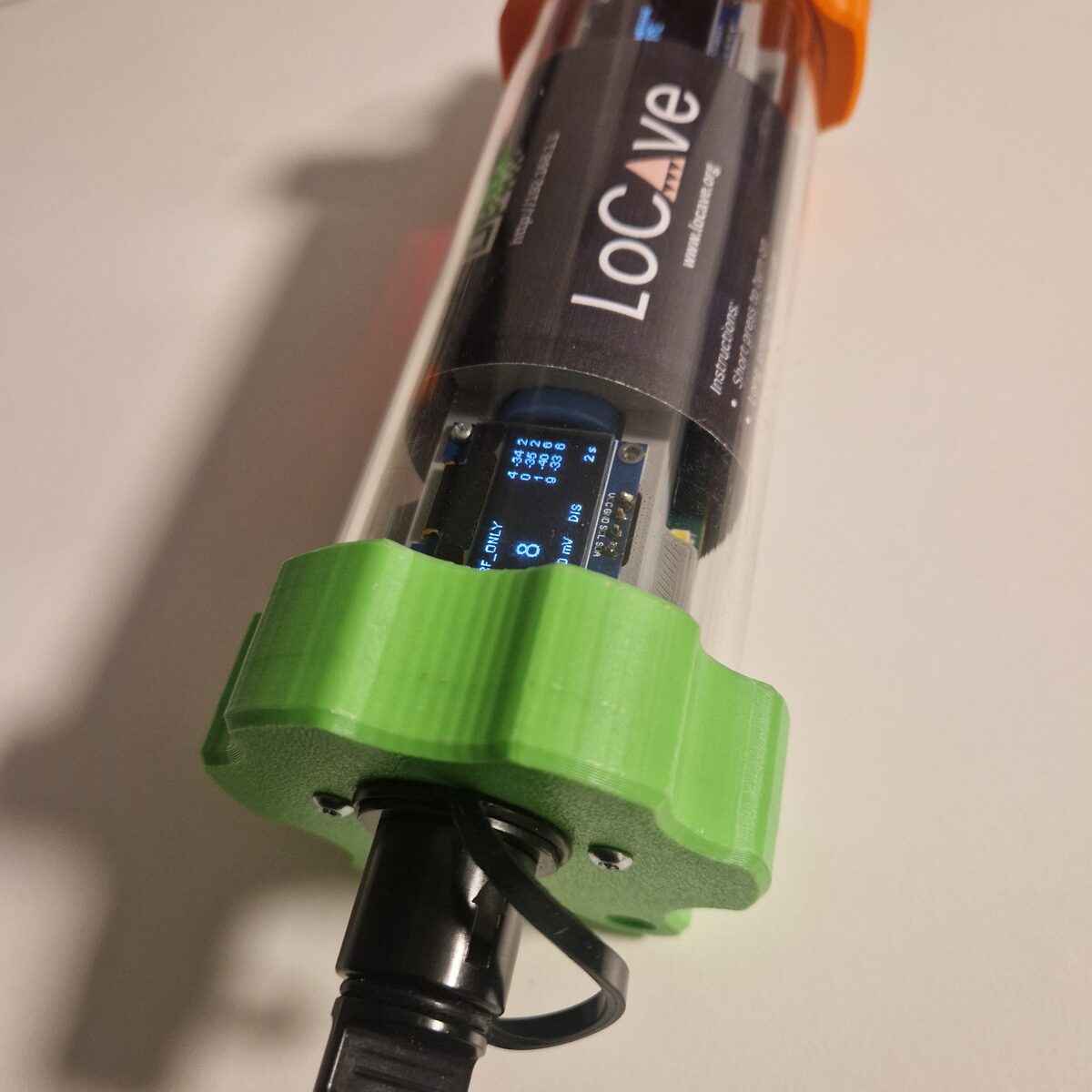 The optical connector on the end cap of a node, with its dust cap on a tether.