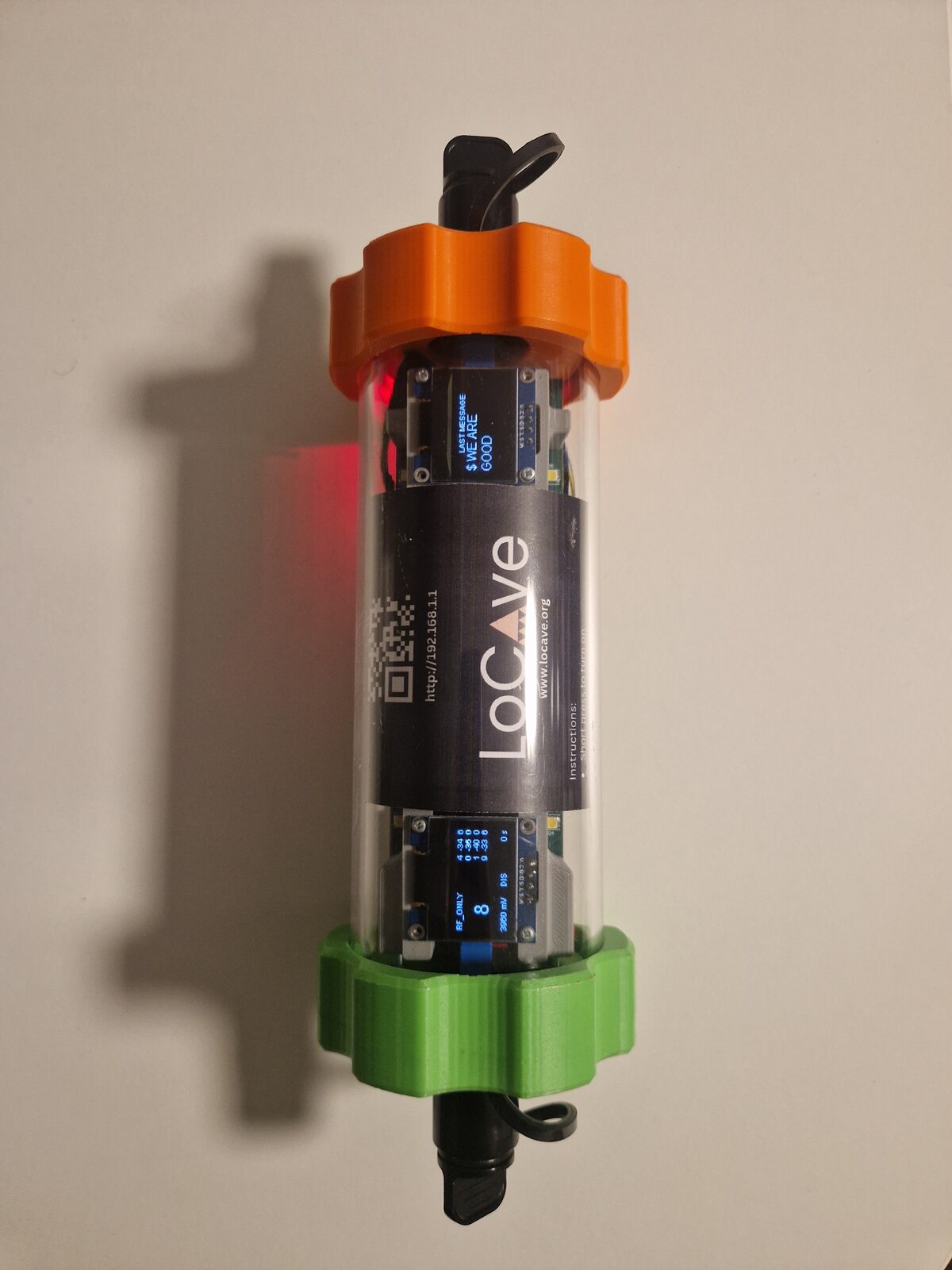 A LoCave node: a clear tube with orange and green end caps, two small displays and the LoCave label.