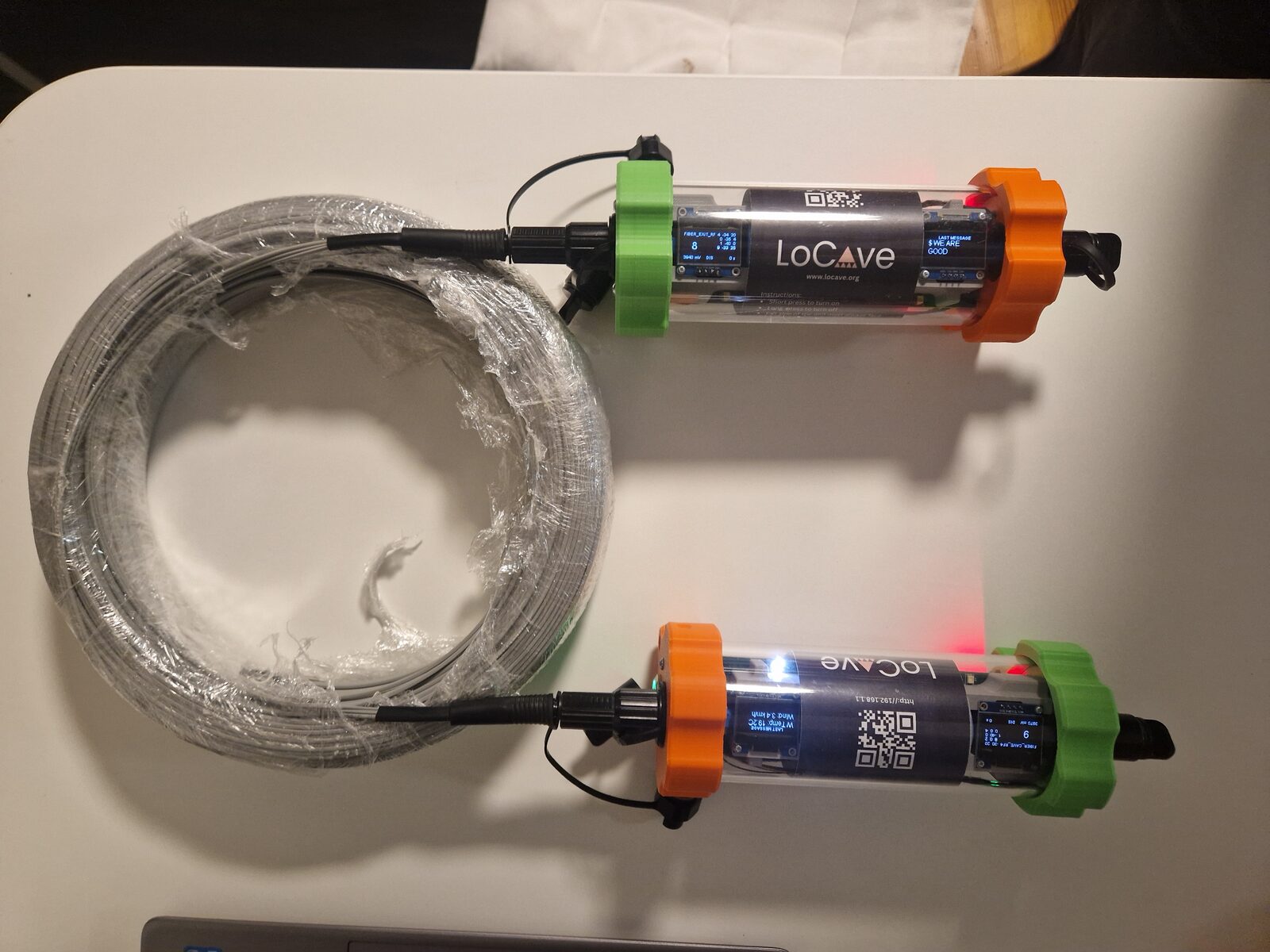 Two LoCave nodes joined by a length of fibre, with the rest of the fibre on a coil beside them.
